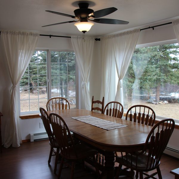 A dining room table with six chairs and a ceiling fan.