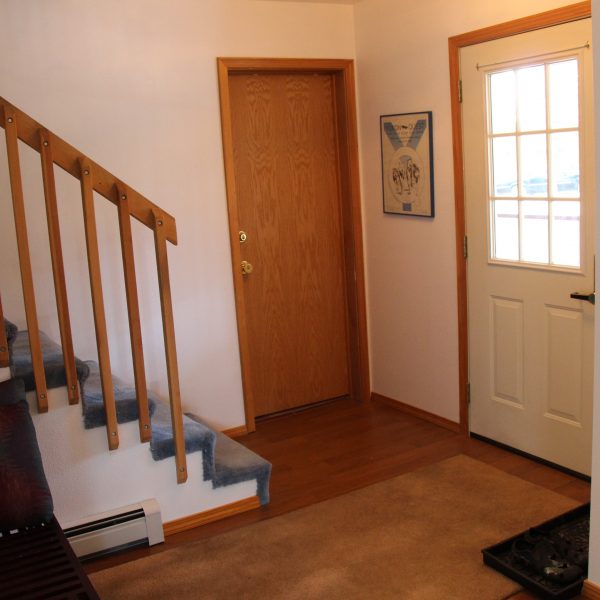 A white door and wooden stairs in the hallway.