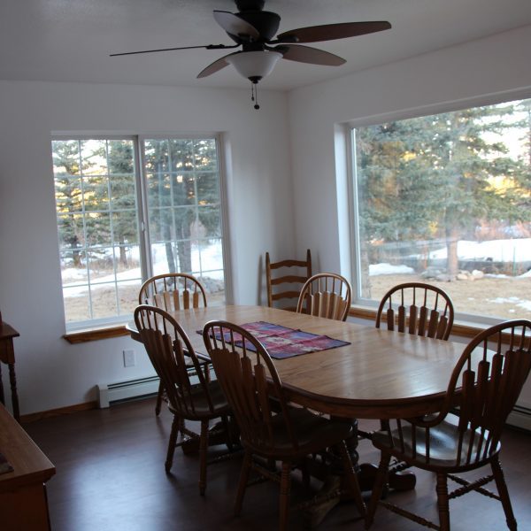 A dining room table with chairs and a fan